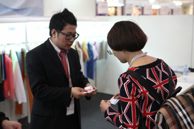Visitenkarten werden immer rege ausgetauscht. Blick auf einen asiatischen Messestand