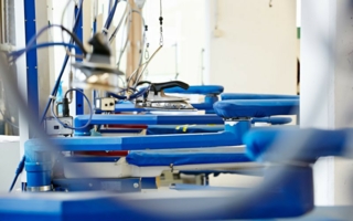 Auf Industrie-Bügelanlagen erhält die Kleidung das perfekte Finish. Photo: Packservice